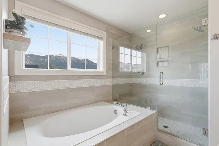 Soaking tub with deck-mounted faucet and mountain scenery through the large window