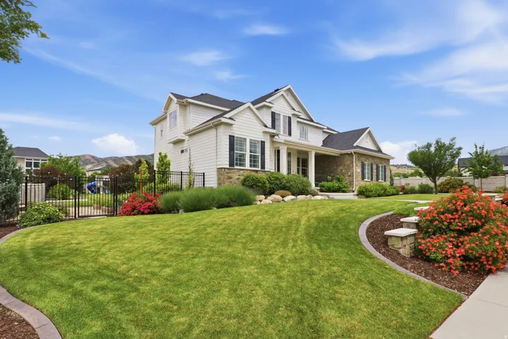 Stately two-story residence featuring light-colored siding and stone veneer accents