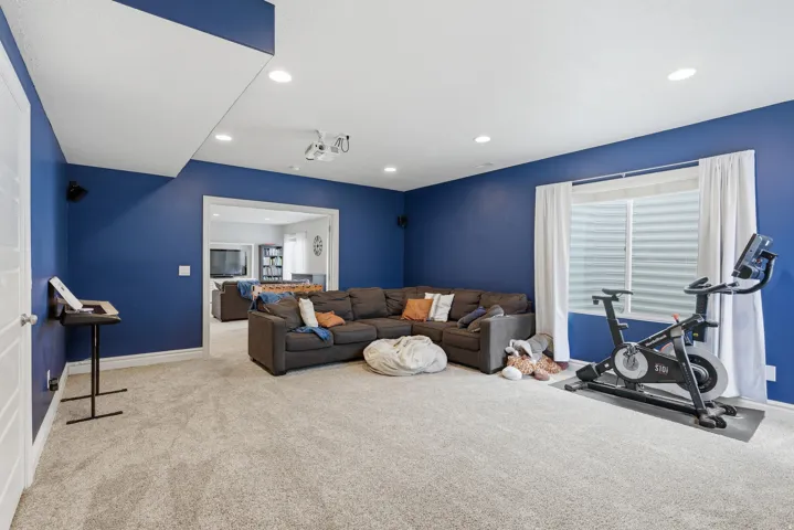 Spacious room featuring plush carpet flooring, recessed lighting, and a white trim baseboard