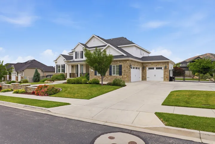 Stone and siding exterior featuring a three-car garage and a paved driveway