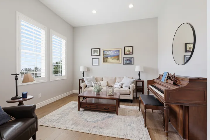 Spacious room featuring wood-finish flooring, tall windows with white plantation shutters, neutral wall tones, and recessed lighting