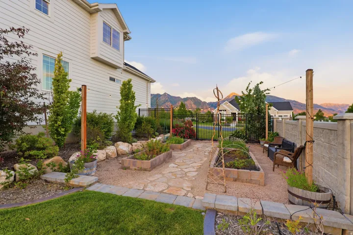 Expansive backyard featuring a manicured lawn, established landscaping, and a flagstone patio