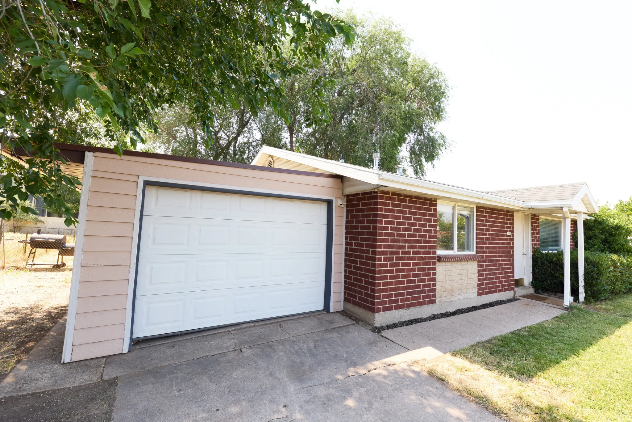 Exterior featuring a white garage door, red brick siding, and a covered front entry with white columns