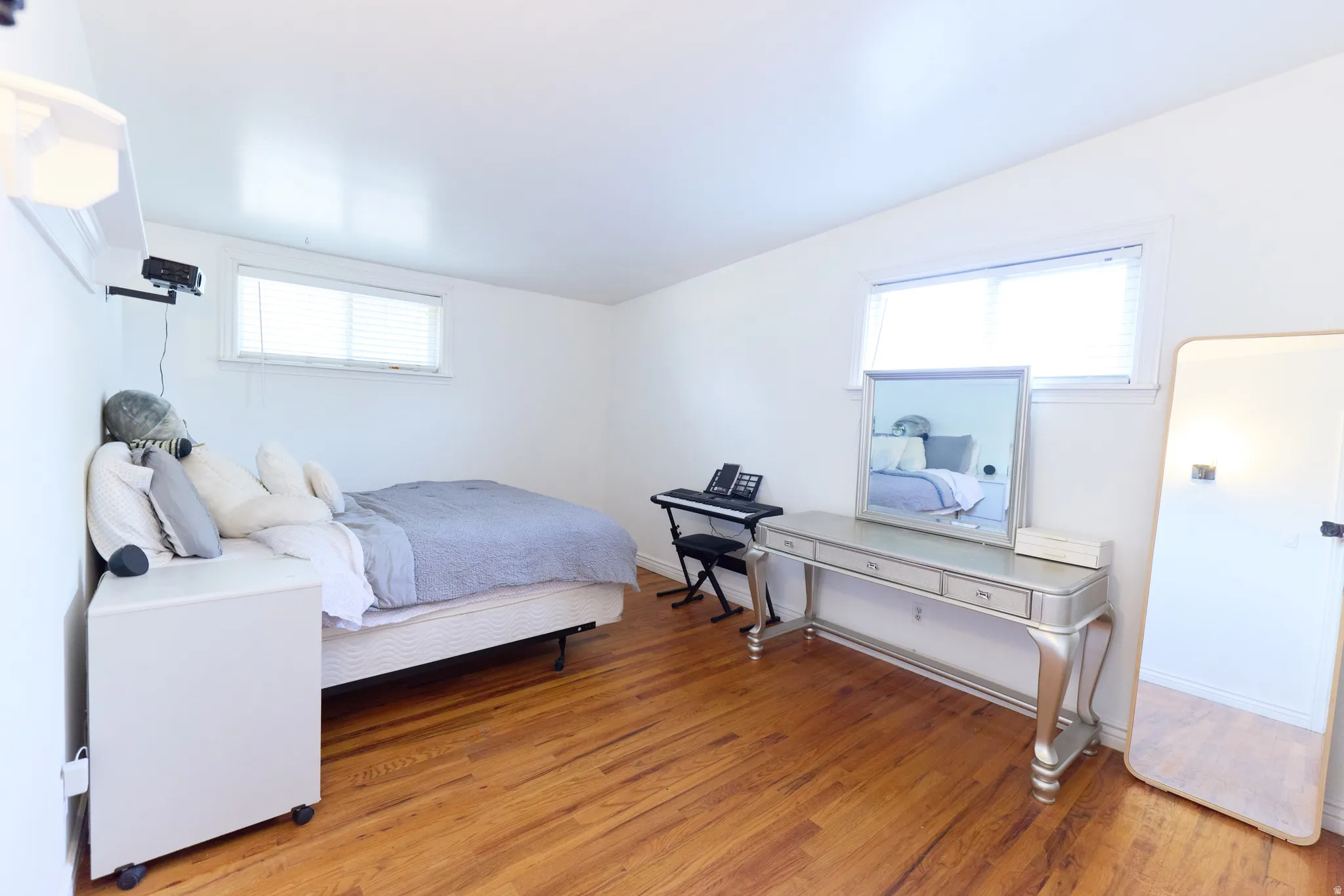 Room featuring wood-finish flooring, white walls, and multiple windows with blinds