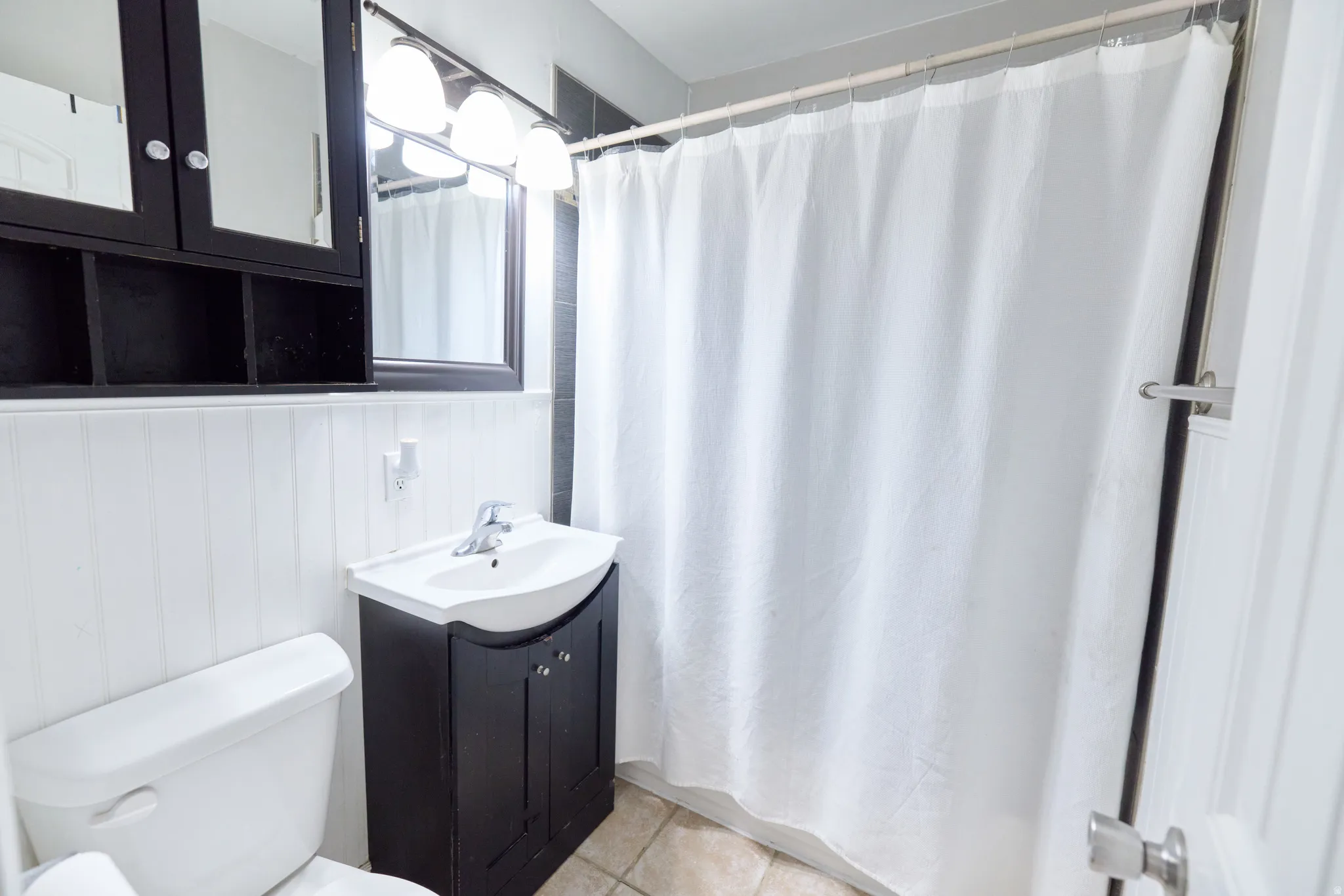 Bathroom featuring a dark wood vanity with integrated sink, coordinating mirror, and wall-mounted light fixture