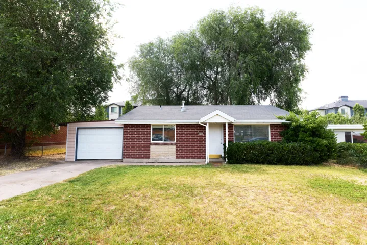 Single-story residence featuring a brick facade with stone detailing, a white entry door with an overhang, and a front yard with mature landscaping