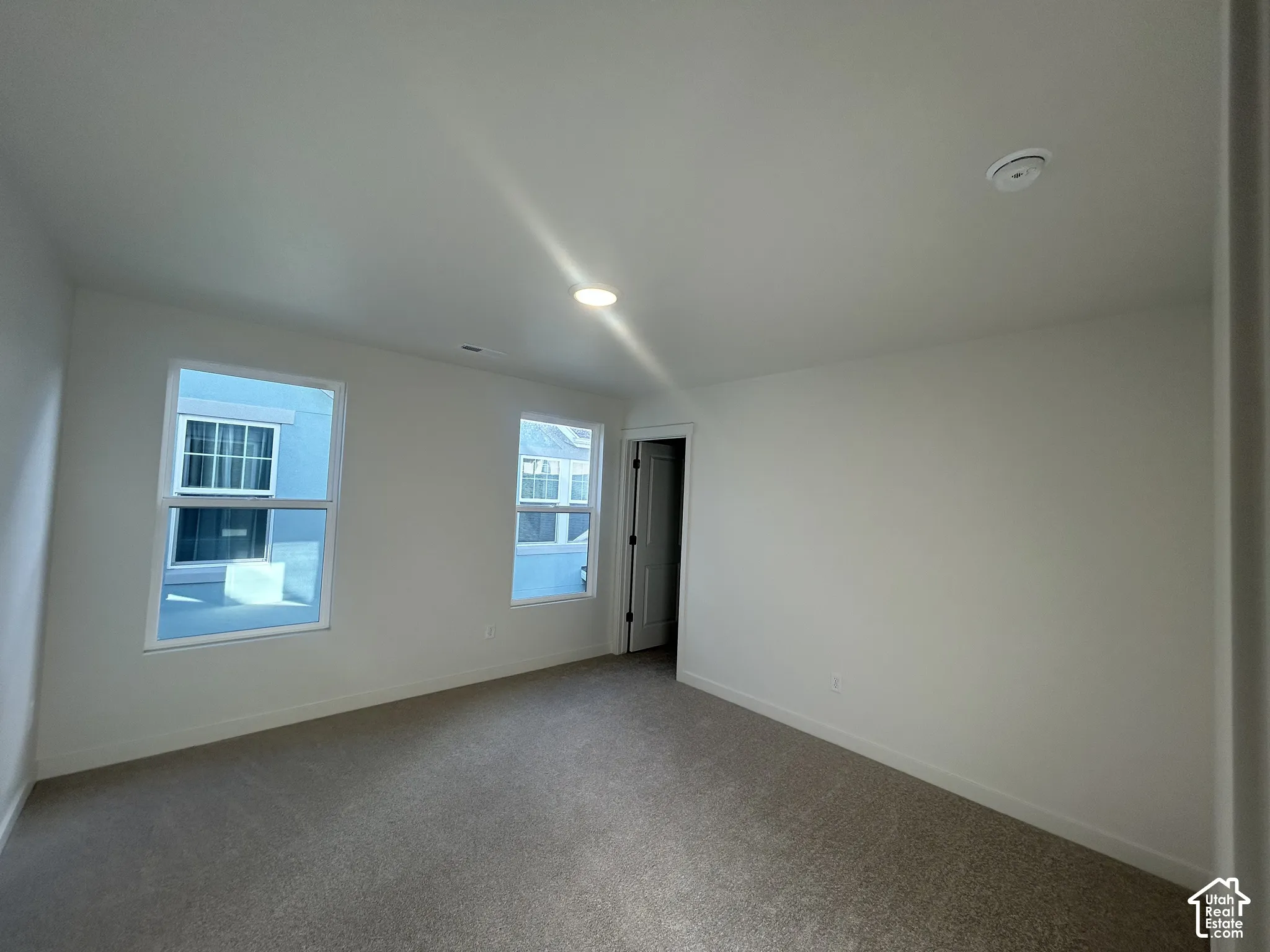 Neutral-toned interior space featuring carpeting, recessed lighting, and two double-pane windows