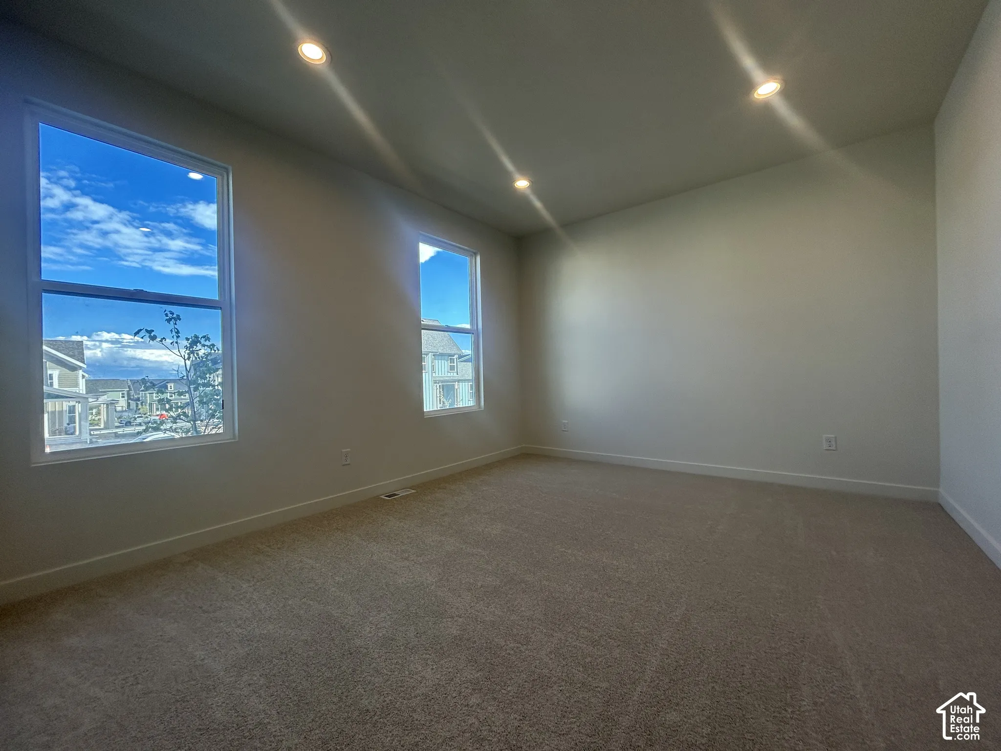 Neutral-toned interior space featuring recessed ceiling lighting, wall-to-wall carpeting, and dual windows