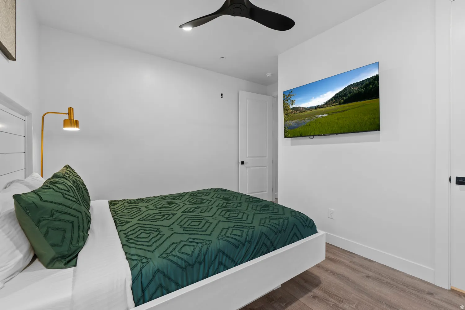 Spacious room featuring wood-finish flooring and crisp white walls