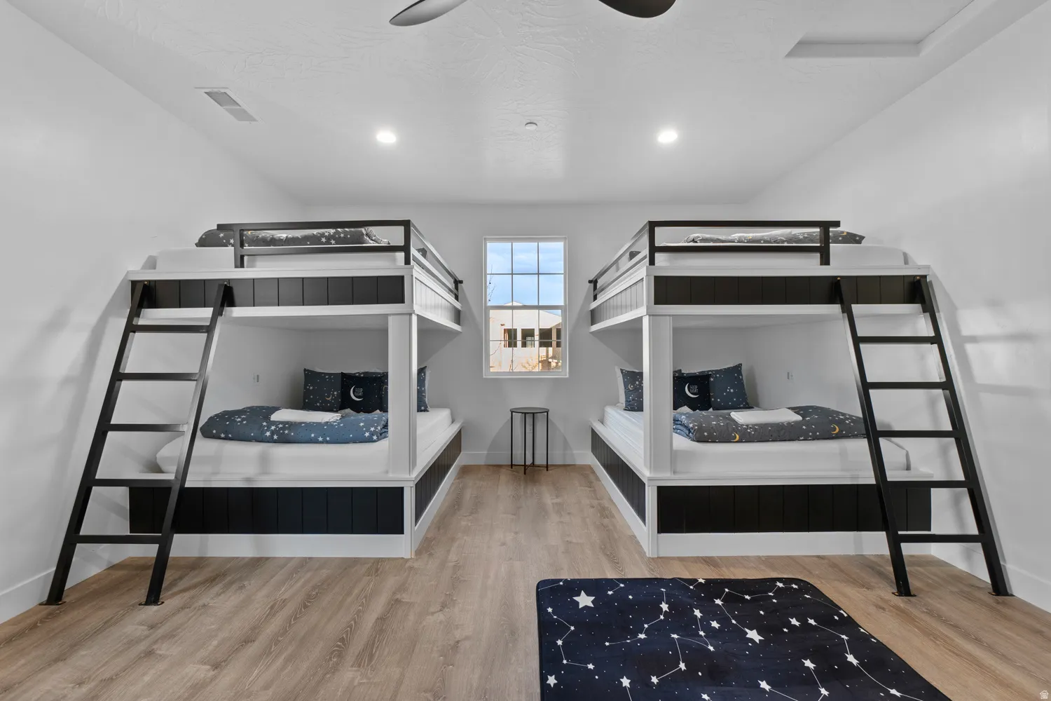 Bedroom featuring two built-in bunk beds, wood-finish flooring, and a single pane window