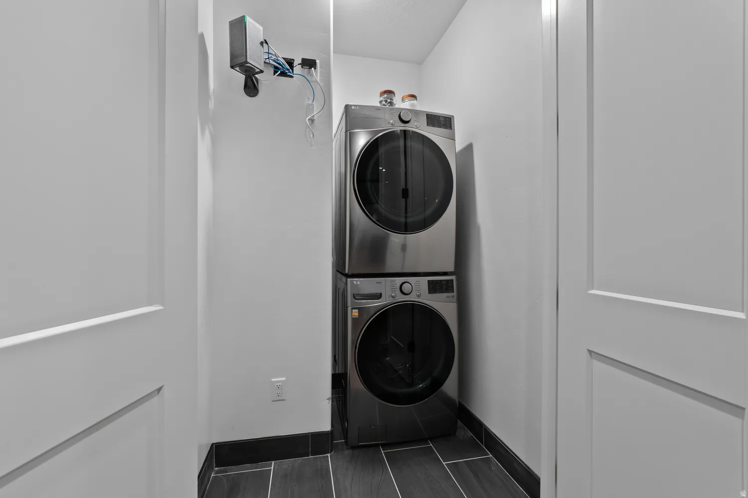Dedicated laundry closet featuring a stacked washer and dryer, wood-finish tile flooring, and dark baseboards