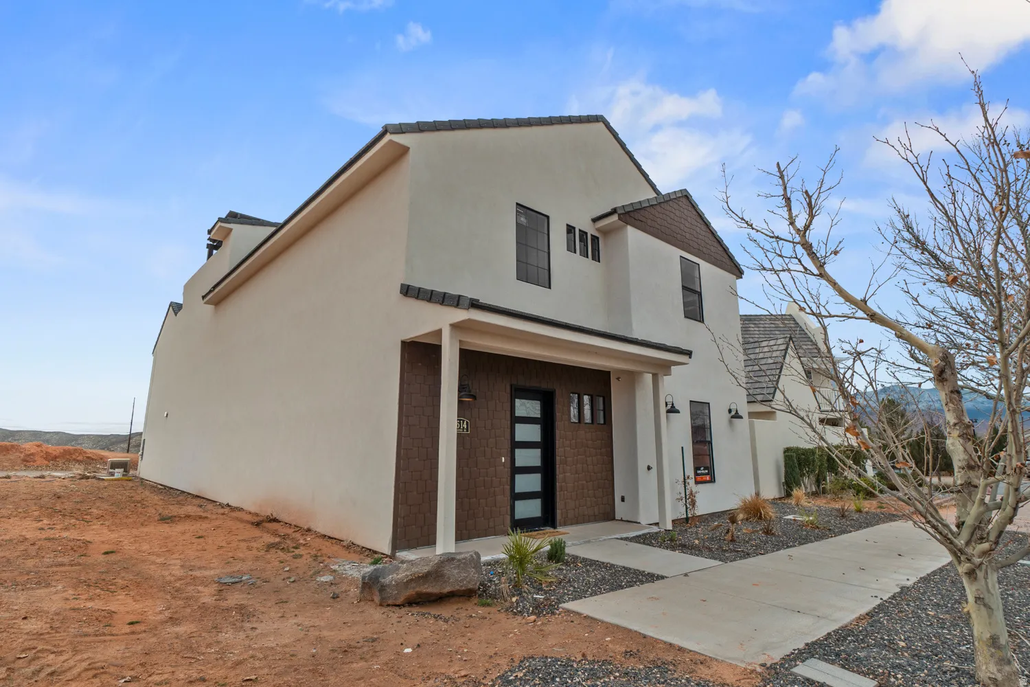 Contemporary two-story exterior featuring a white stucco finish and dark tile roof accents