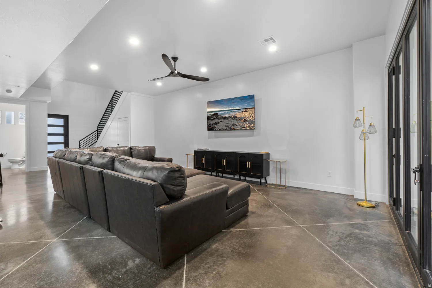 Spacious living area featuring polished concrete flooring, recessed lighting, and a contemporary ceiling fan