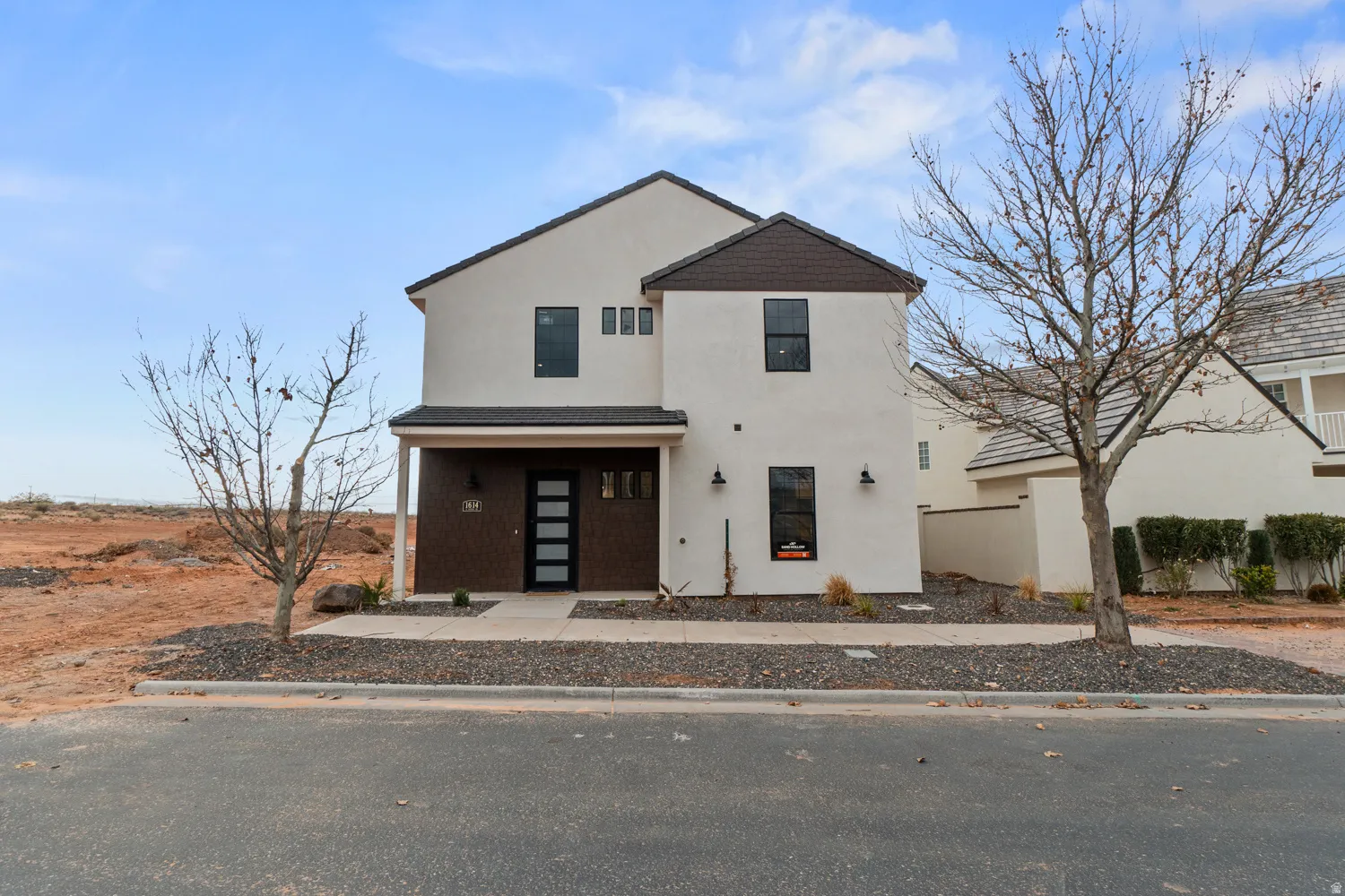 Contemporary two-story residence featuring a stucco exterior and a dark, low-slope roofline