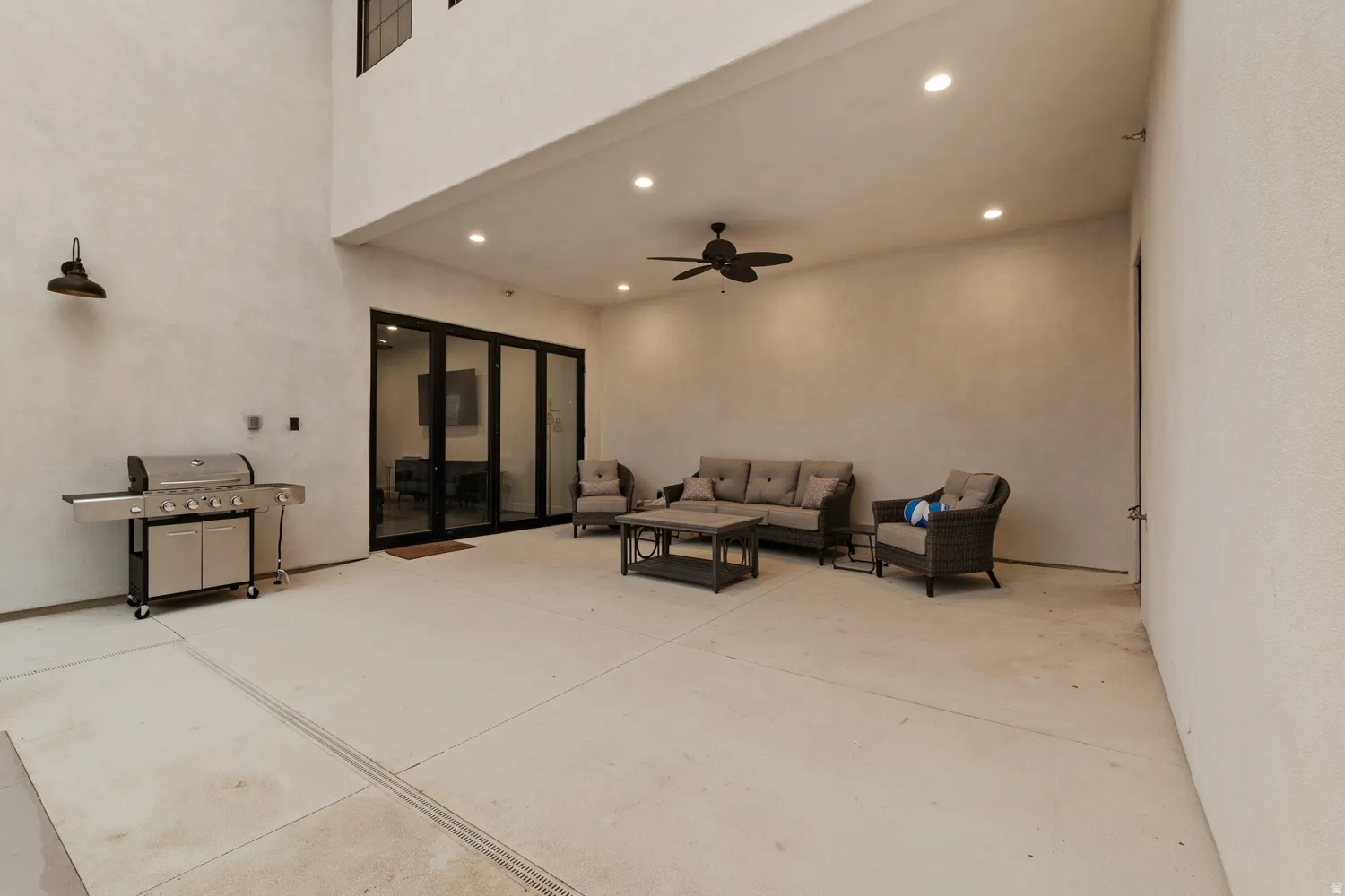 Expansive outdoor patio area featuring a ceiling fan, recessed lighting, and large folding glass doors