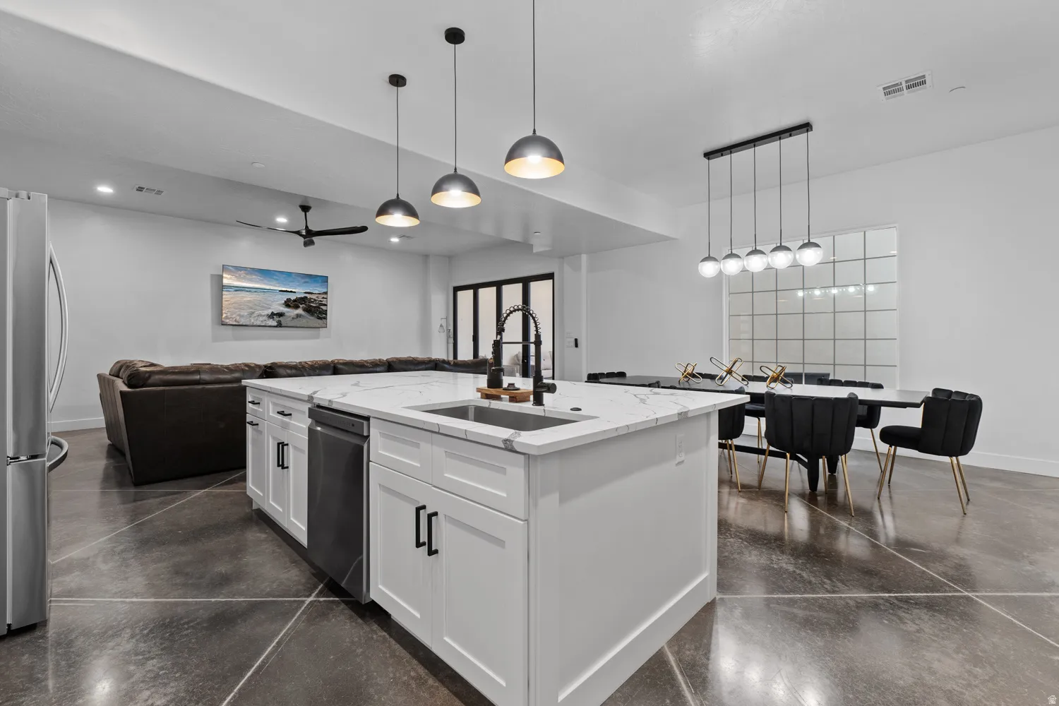 Kitchen island featuring a white countertop with integrated sink, black faucet, and pendant lighting