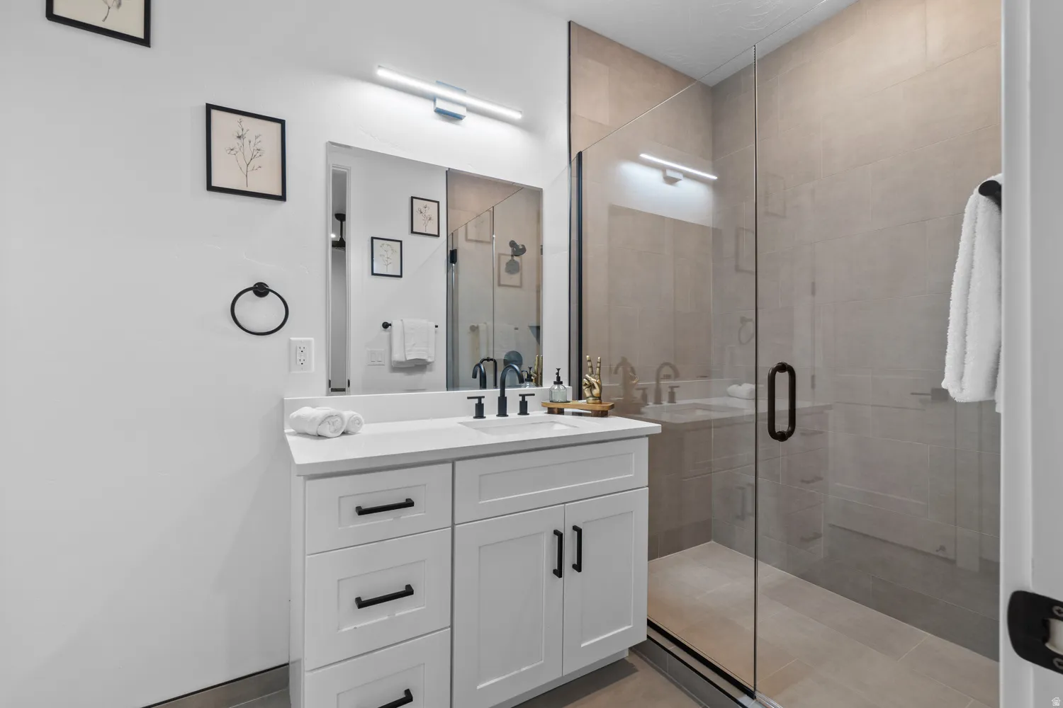 Contemporary bathroom featuring a frameless glass shower enclosure with neutral-toned wall and floor tiling
