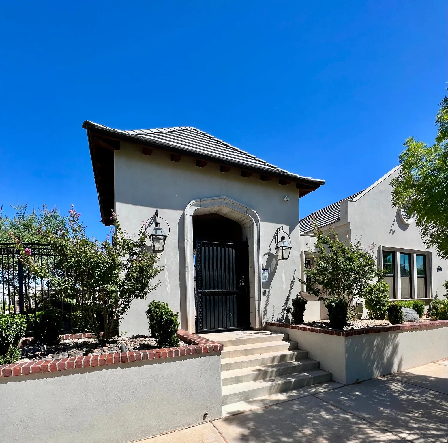 Stucco exterior with a tiled roofline and carved stone archway entrance