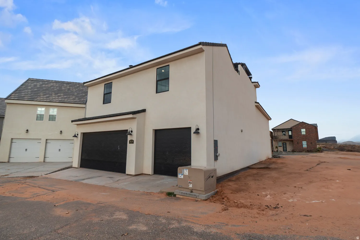 Contemporary stucco exterior featuring a multi-car garage with dark paneled doors and accent lighting