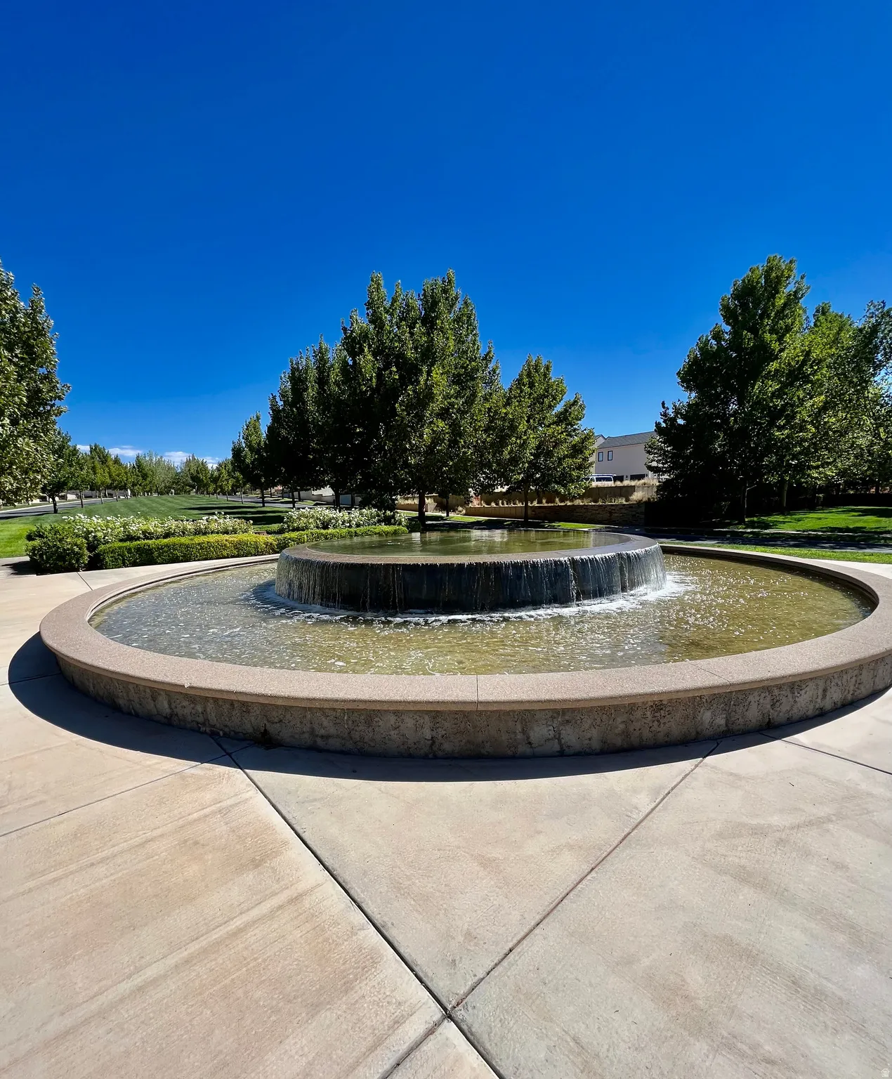 Circular water feature with a textured stone basin, surrounded by a paved hardscape