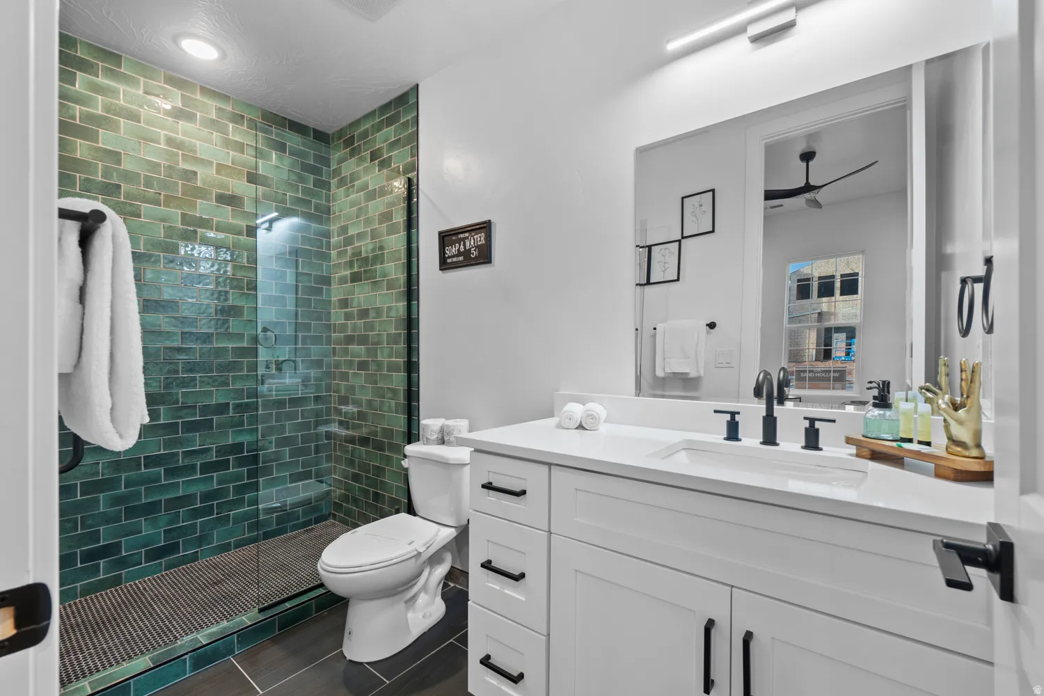 Bathroom featuring a walk-in shower with green subway tile, frameless glass enclosure, and a built-in shower bench