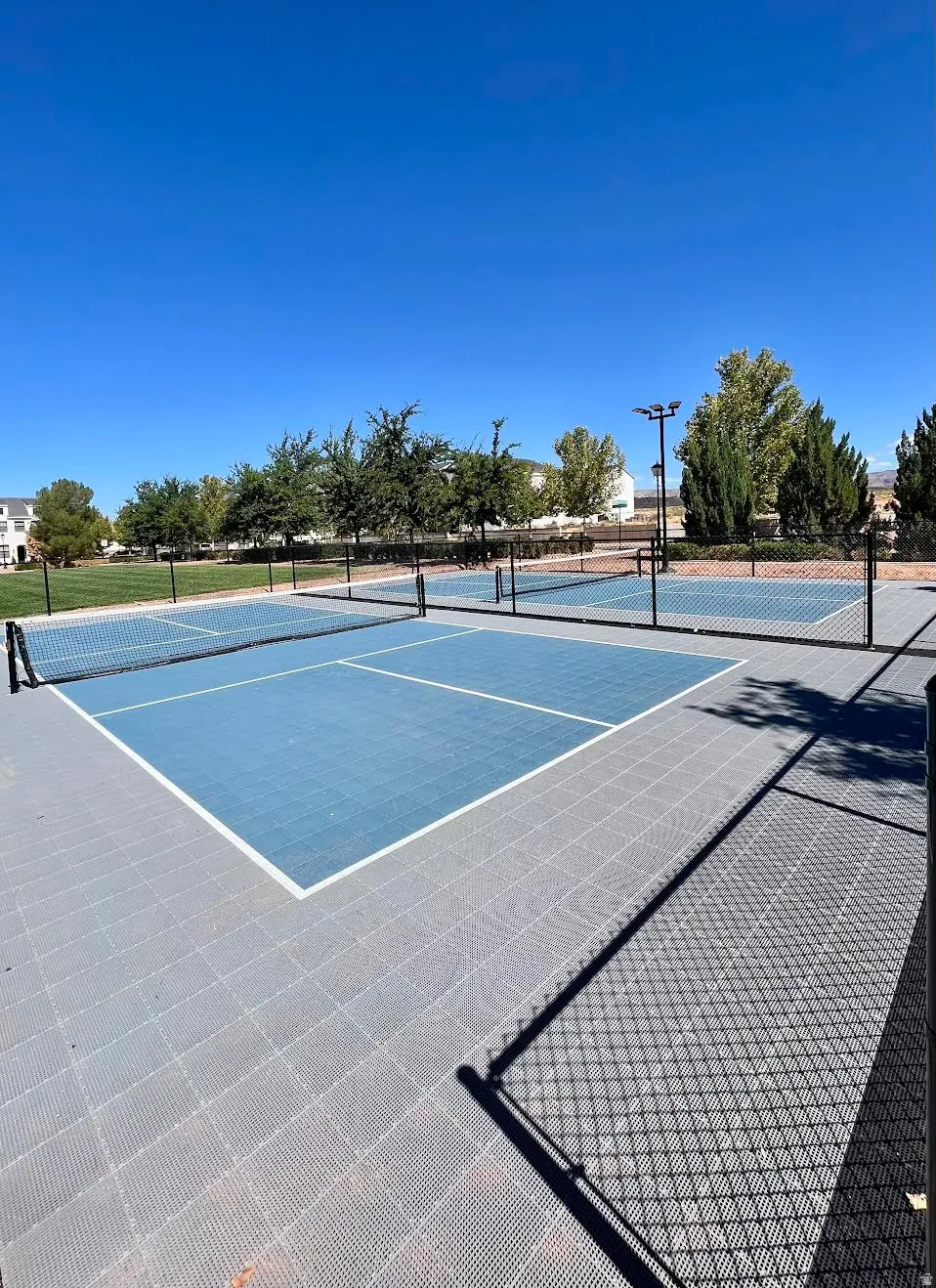 Dedicated pickleball courts featuring a blue playing surface, white boundary lines, and surrounding black chain-link fencing