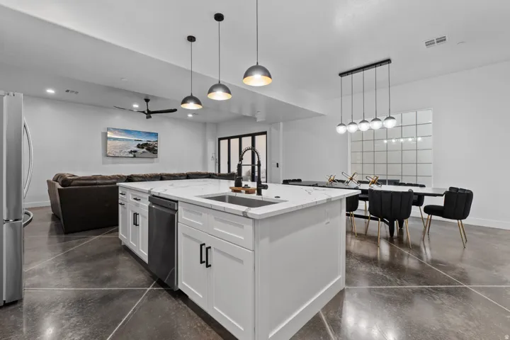 Kitchen island featuring a white countertop with integrated sink, black faucet, and pendant lighting