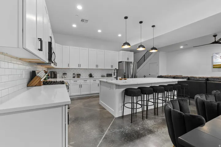Spacious open-concept kitchen featuring white shaker cabinetry, white subway tile backsplash, and light-toned countertops