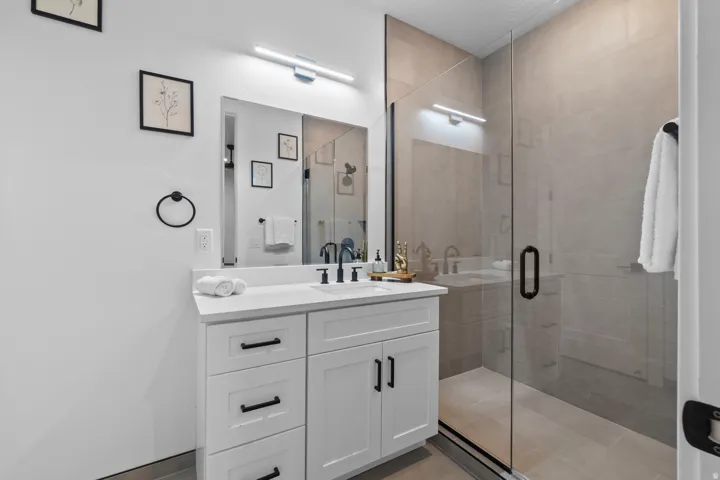 Contemporary bathroom featuring a frameless glass shower enclosure with neutral-toned wall and floor tiling