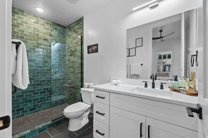Bathroom featuring a walk-in shower with green subway tile, frameless glass enclosure, and a built-in shower bench
