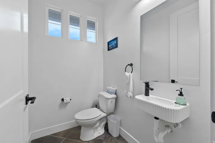 Contemporary powder room featuring a wall-mounted fluted sink, a rectangular mirror, and matte black fixtures