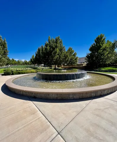 Circular water feature with a textured stone basin, surrounded by a paved hardscape