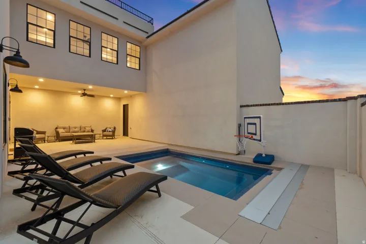 Private courtyard with swimming pool, covered patio, wall-mounted sconces, recessed lighting, and a ceiling fan