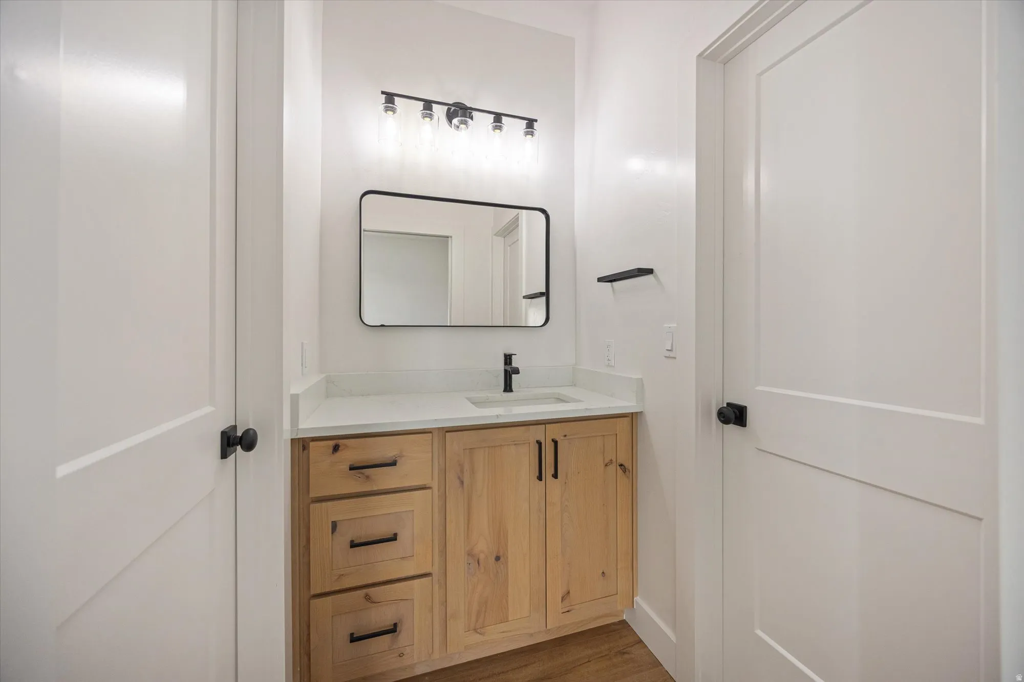Bathroom vanity featuring natural wood cabinetry, a light-toned countertop, and an undermount sink