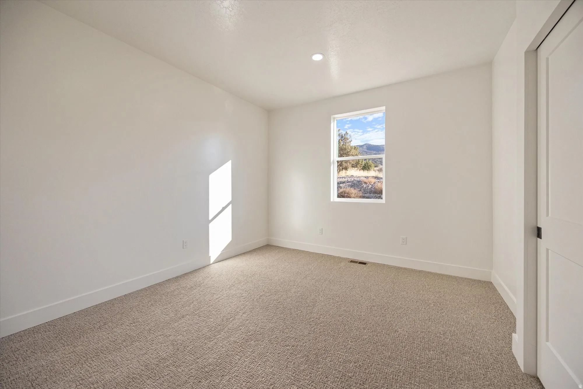 Carpeted room featuring a single window and recessed lighting
