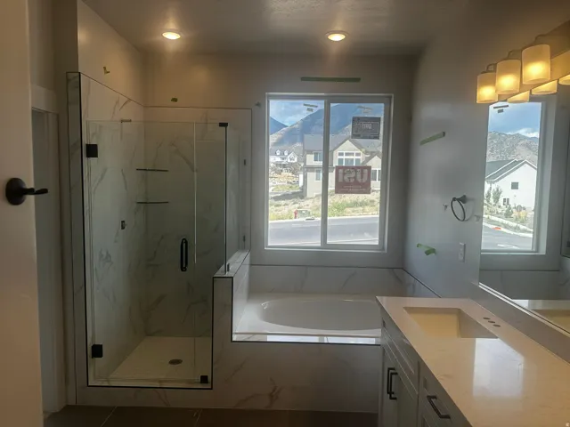 Walk-in shower with clear glass enclosure and tile surround