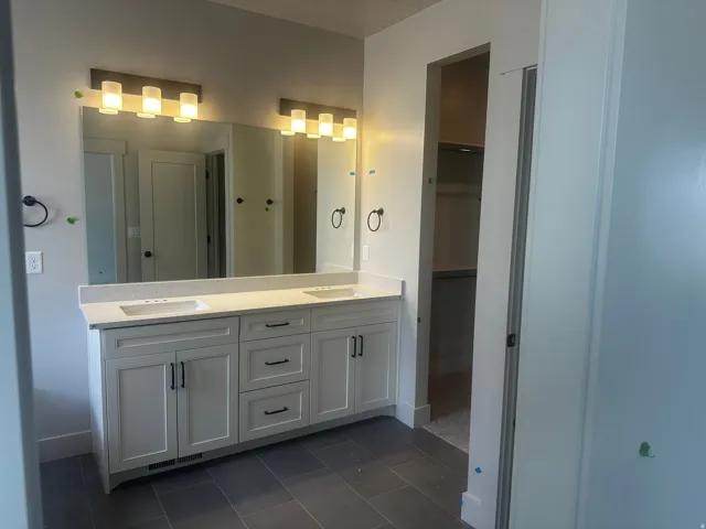 Dual vanity with undermount sinks, light-toned countertop, and modern light fixtures