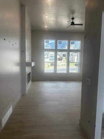 Recessed ceiling lighting, modern ceiling fan, wood-finish flooring, electric fireplace with white mantle, and large windows