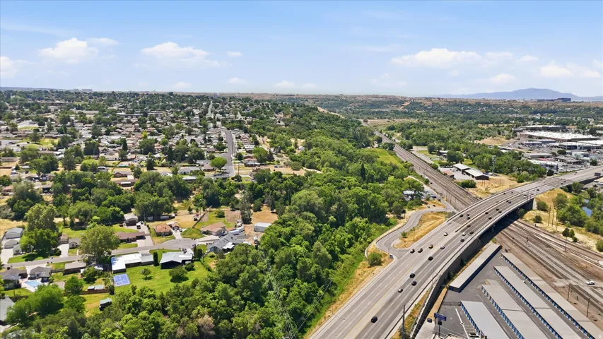 Aerial perspective showcasing a residential area with extensive tree coverage, multi-lane roadways, and commercial buildings