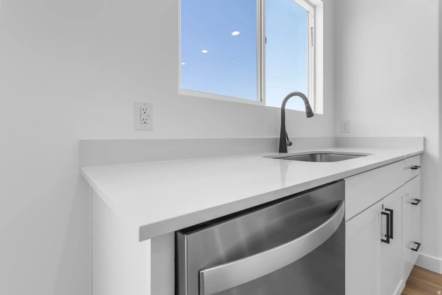 Crisp white cabinetry with matte black hardware, a stainless steel under-mount sink, and a gooseneck faucet