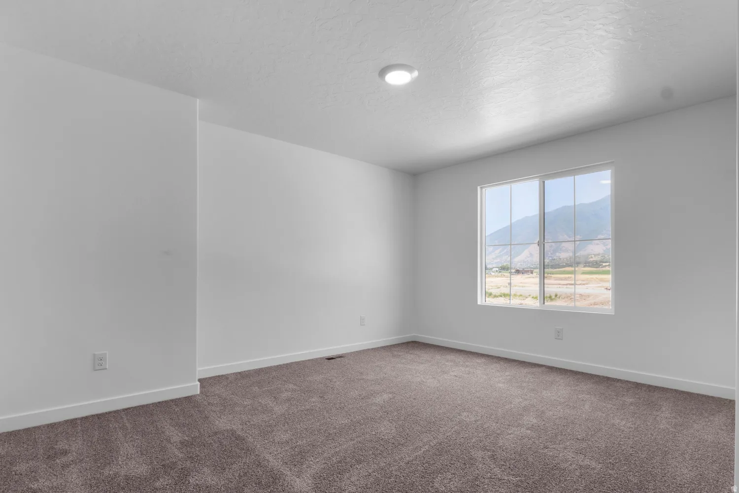 Spacious room featuring neutral paint, brown carpet, white trim, recessed lighting, and a window with mountain scenery