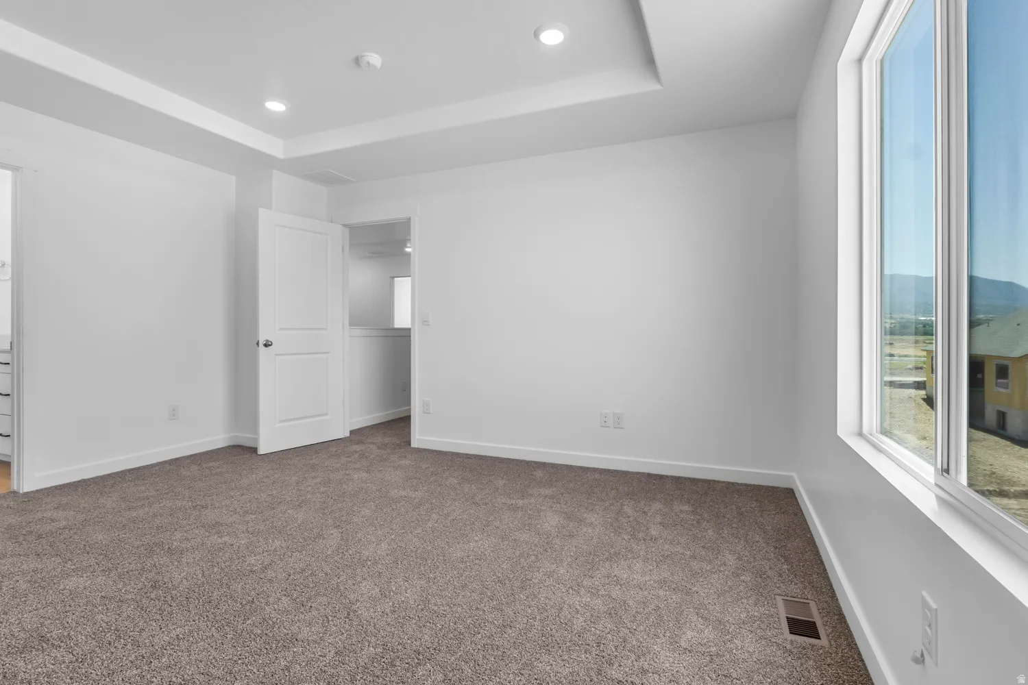 Spacious room featuring a tray ceiling, recessed lighting, and large windows