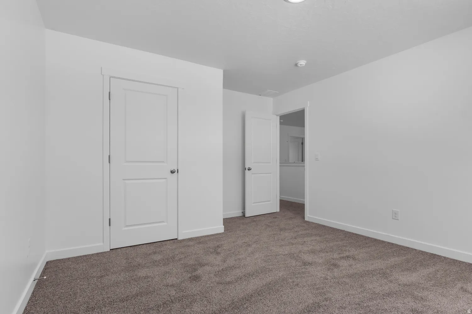 Spacious room featuring neutral carpeting and white walls