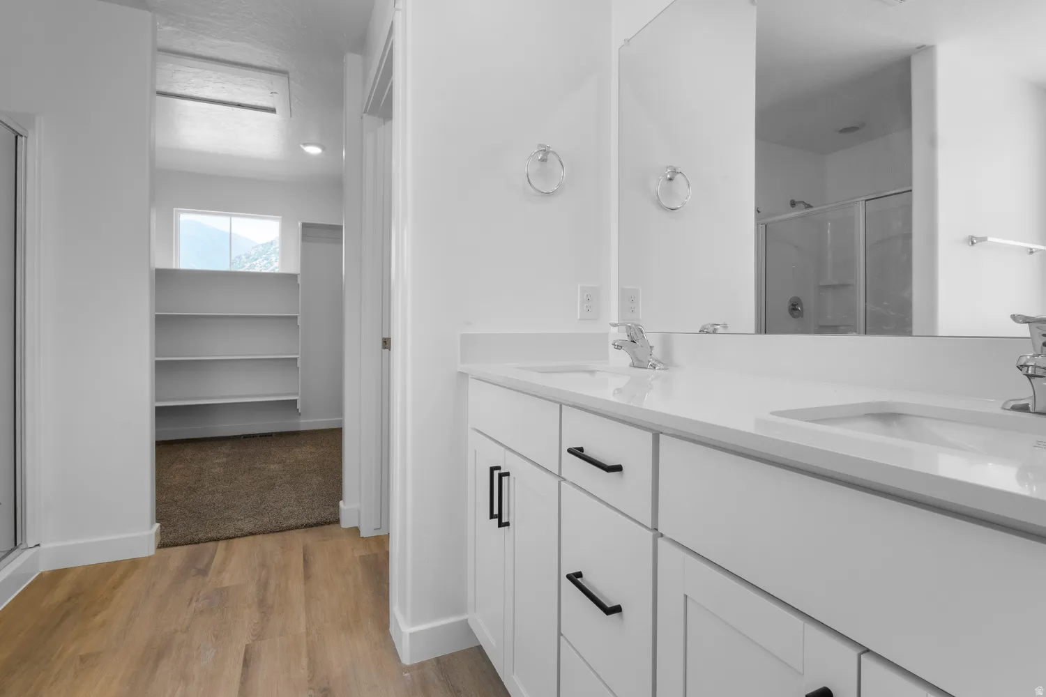 Dual vanity with white countertops, chrome fixtures, and black cabinet hardware
