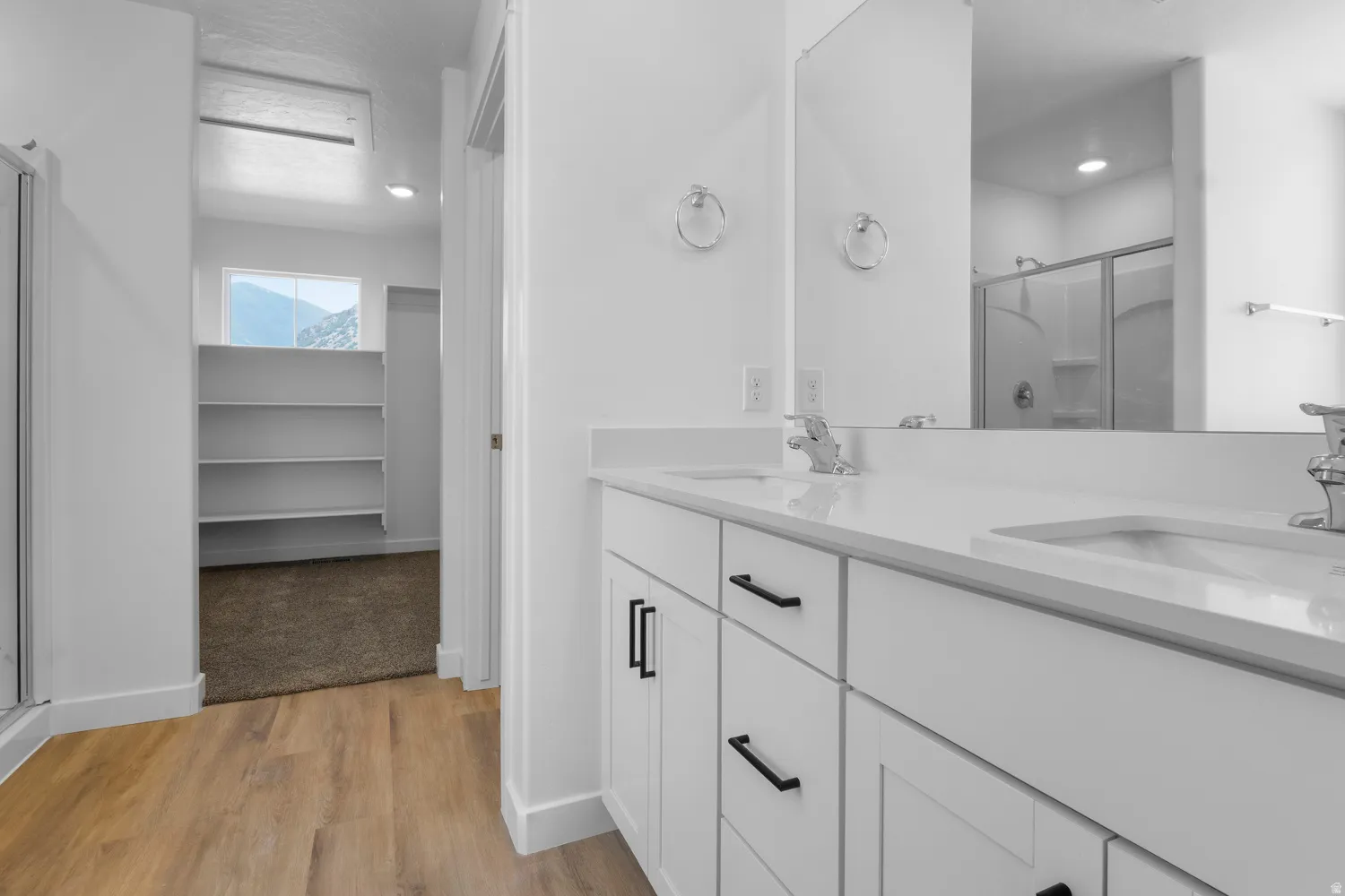 Dual white vanity with undermount sinks, chrome faucets, and black hardware