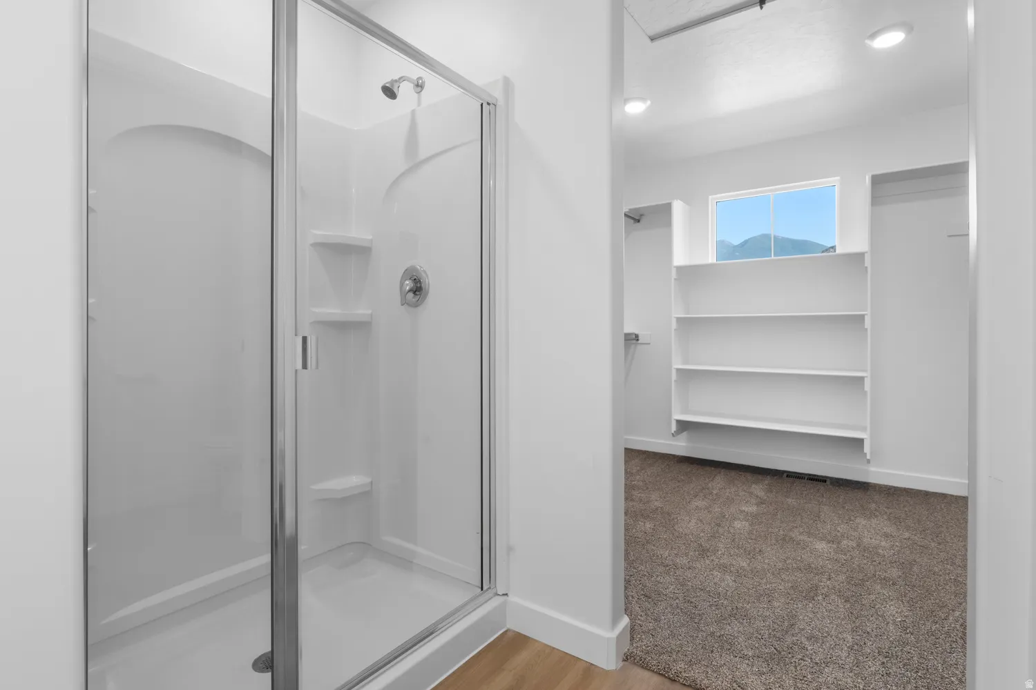 Walk-in shower with clear glass enclosure and built-in shelving