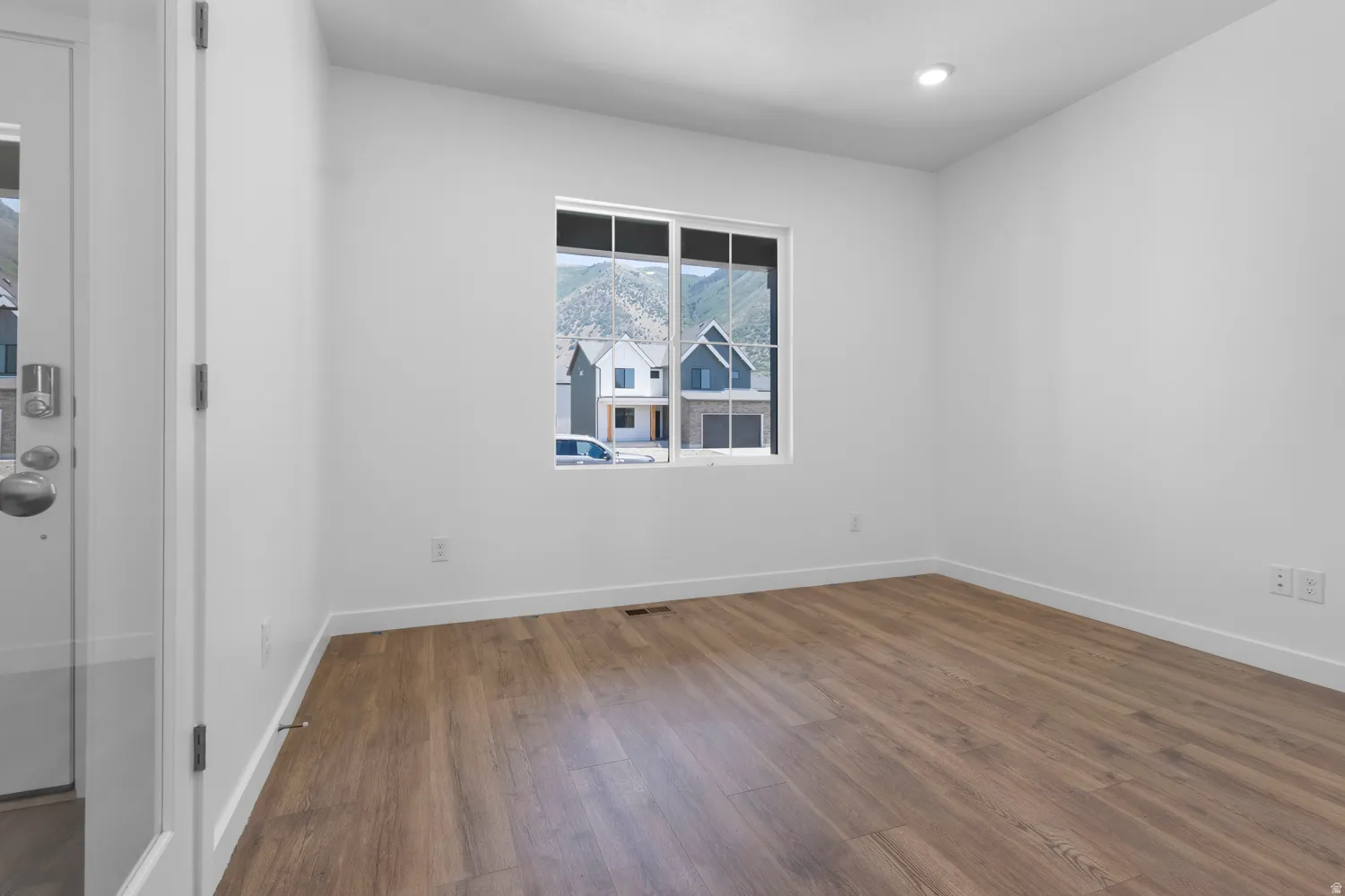 Room featuring wood-finish flooring, recessed lighting, and a window with mountain scenery