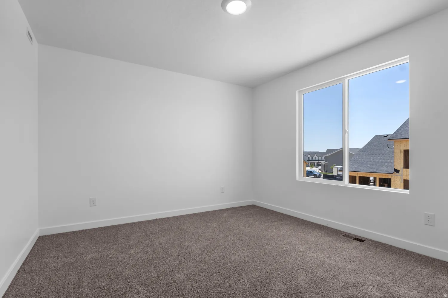 Bright room with a large window, neutral carpeting, and white baseboards