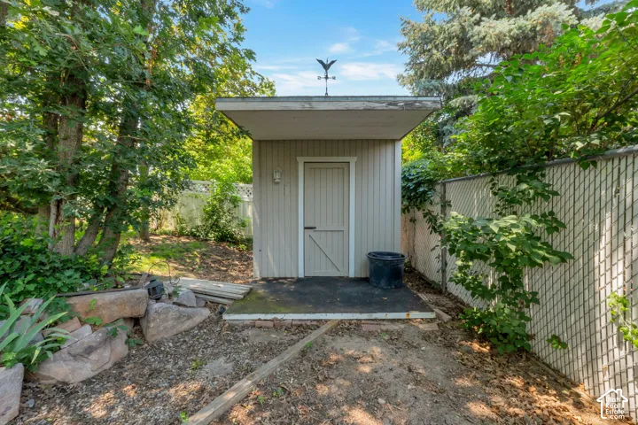 Detached storage shed featuring vertical siding, an overhanging roofline, and a weather vane accent