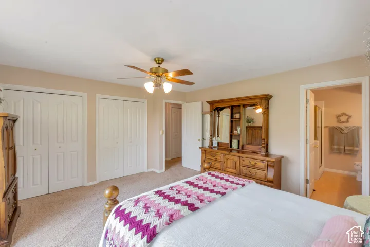 Carpeted room featuring dual bi-fold closet doors and a ceiling fan with integrated lighting